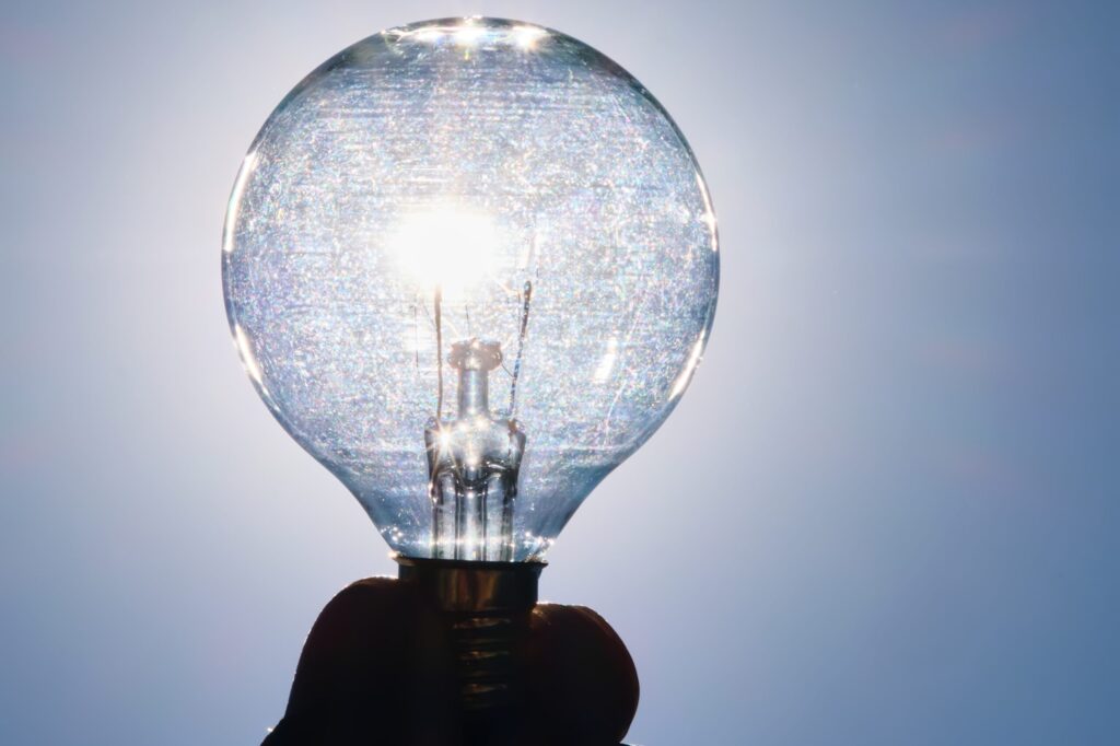 light-bulb-in-hand-against-the-sky-with-a-sun-2023-11-27-05-26-08-utc-1-1-scaled.jpg